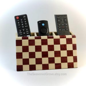 Peut inclure: Un porte-télécommande en bois avec un motif de damier naturel et bordeaux. Il contient trois télécommandes noires. TheSeasonedGrove.etsy.com est imprimé en bas.