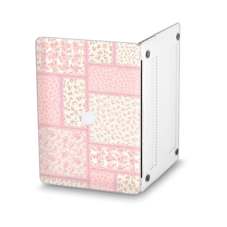 Peut inclure: Une coque d'ordinateur portable avec un motif patchwork. L'&eacute;tui pr&eacute;sente un motif de carr&eacute;s de tissu floral roses et cr&egrave;me. Le logo Apple blanc de l'ordinateur portable est visible. L'&eacute;tui est fait d'un mat&eacute;riau transparent et protecteur.
