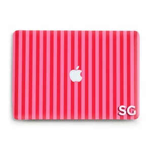Könnte beinhalten: Eine pink-rot gestreifte Laptop-Hülle mit dem Apple-Logo in der Mitte. Die weißen Initialen "SG" befinden sich unten rechts. Die Hülle hat eine glänzende Oberfläche.