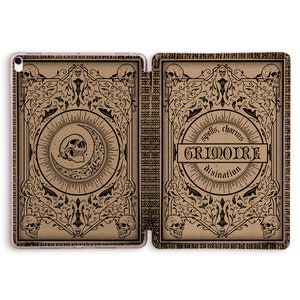 Peut inclure: Étui de tablette marron avec un design vintage avec des crânes, des croissants de lune et des volutes ornées. Le couvercle indique "GRIMOIRE" avec les mots "spells, charms, divination". L'étui est ouvert, révélant la tablette à l'intérieur.