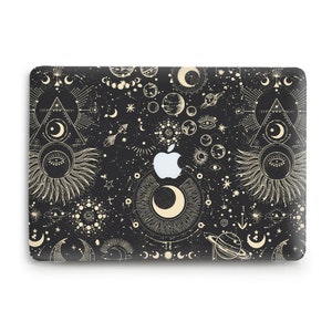 Może przedstawiać: Czarna skórka na laptopa z złotym wzorem kosmicznym. Wzór zawiera księżyce, gwiazdy, planety i inne symbole kosmiczne. Logo Apple jest widoczne na skórce.