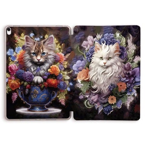 Puede incluir: Dos gatos rodeados de flores coloridas. Un gato está sentado en un jarrón azul y blanco, el otro está de pie en un ramo de flores.