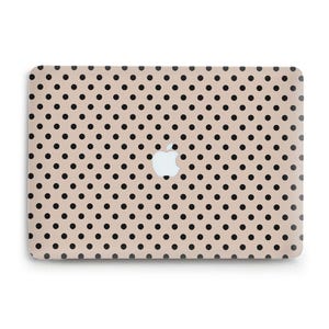 Pode incluir: Uma capa para laptop com fundo bege e um padrão repetido de bolinhas pretas. O logotipo da Apple é visível no centro. A capa é retangular e tem cantos arredondados.