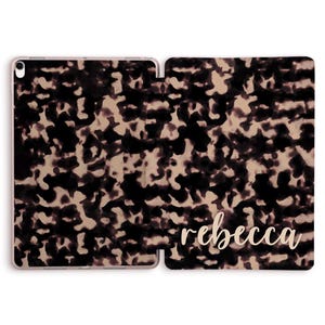 Può includere: Una custodia per iPad con un motivo a tartaruga nera e bianca e il nome "rebecca" scritto in lettere dorate.
