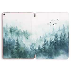 May include: An open tablet case featuring a watercolor forest scene. The design showcases a misty forest with evergreen trees in shades of green and blue. Silhouettes of birds fly across the top, adding a touch of nature.
