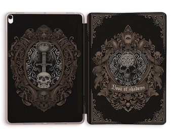 May include: A black iPad case with a gold ornate design featuring a skull and sword on the front and a skull with a pentagram on the back. The text "Book of Shadows" is printed on the back.