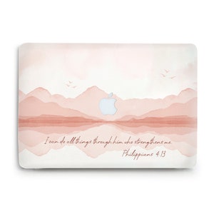 Może przedstawiać: Skórka na laptopa w kolorze różowym i białym z akwarelowym wzorem gór i odbiciem jeziora. Logo Apple jest widoczne w środku obrazu. Tekst "Wszystko mogę w Chrystusie, który mnie umacnia. Filipian 4:13" znajduje się na dole obrazu.