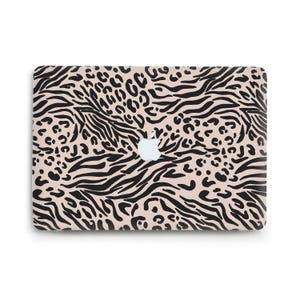 Può includere: Una cover rettangolare per computer portatile con sfondo beige e un motivo animalier nero composto da un mix di strisce zebrate e macchie di leopardo. Un logo Apple bianco è visibile al centro della superficie della cover.