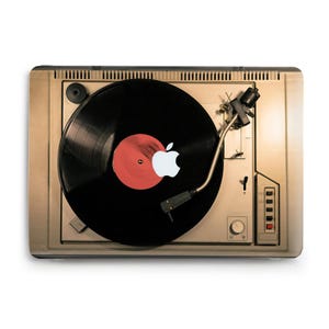 May include: A vintage-style record player with a black vinyl record spinning on the turntable. The record has a red label with a white Apple logo in the center.