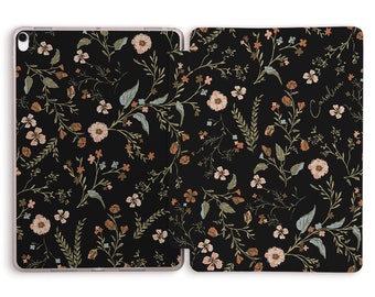 May include: Black iPad case with a floral pattern in shades of pink, brown, and green. The case has a flap that covers the screen and the back of the case has the name "Carolina" written in cursive.