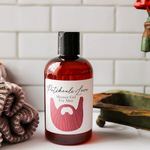 May include: A brown glass bottle with a black cap and a white label that reads "Patchouli Love Shower Gel For Men". The label features a red stylized beard with a blue outline.