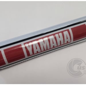 May include: Red and white handlebar pad with black stripes and the word "YAMAHA" printed in white.
