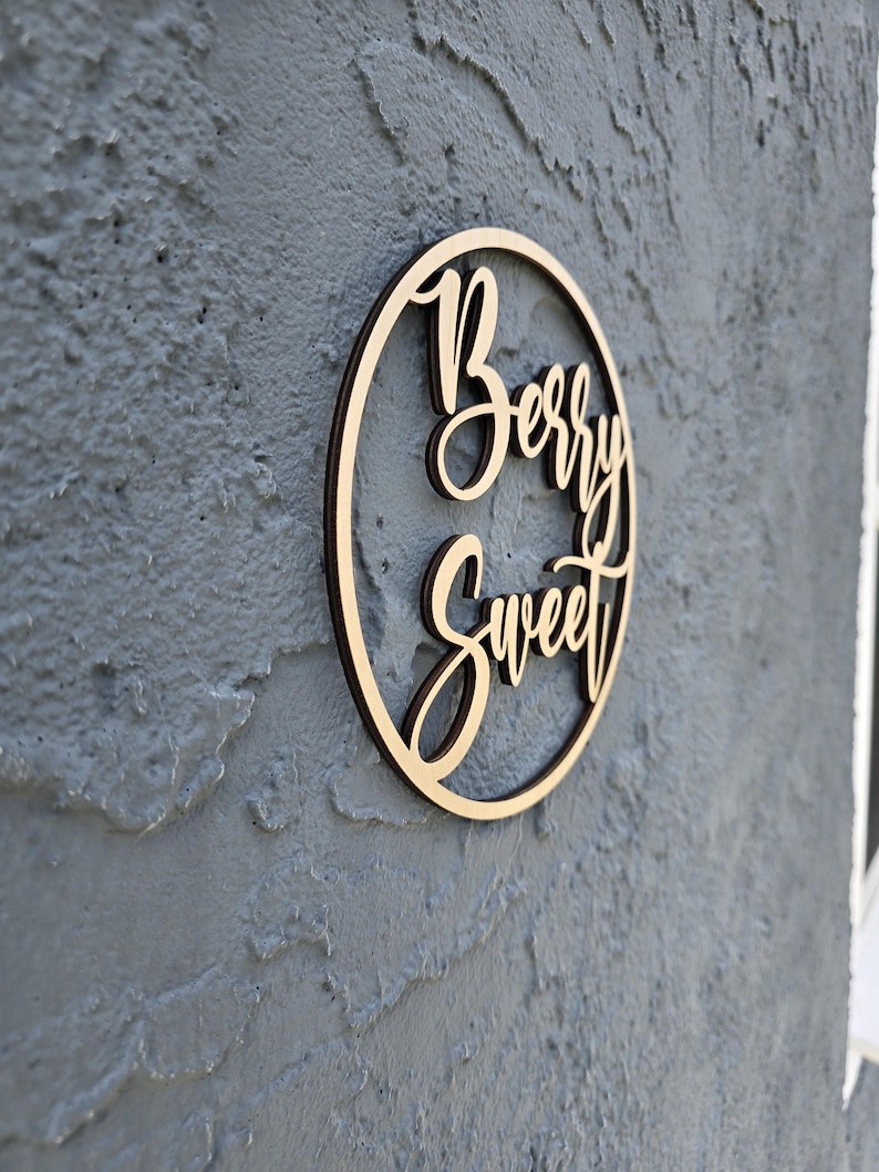 May include: A wooden circle sign with the words "Berry Sweet" written in cursive script.