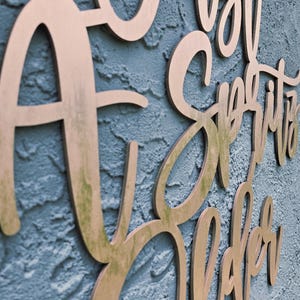 Puede incluir: Letrero de madera con la frase "A Just Spirits Sober" en fuente cursiva. El letrero est&aacute; hecho de madera marr&oacute;n claro y montado en una pared azul texturizada. Las letras est&aacute;n recortadas y tienen una ligera sombra.