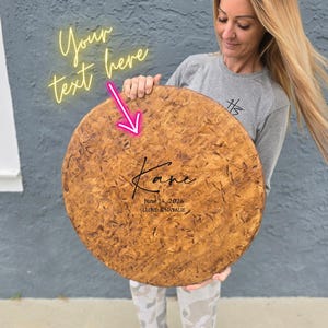 A woman is holding a large wooden plaque with the name "Karen" written on it. The plaque has a personalized message and a date, indicating it is a custom-made item for someone named Karen.