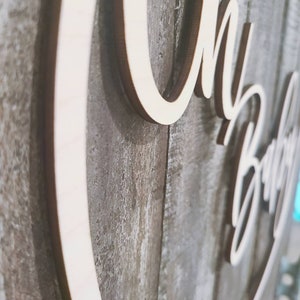May include: Wooden sign with the words "Oh Baby" in a cursive font. The sign is attached to a rustic wooden background.