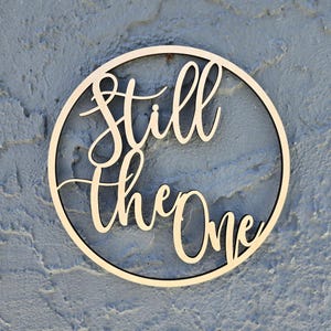 May include: A wooden circle with the words "Still the One" written in cursive script.