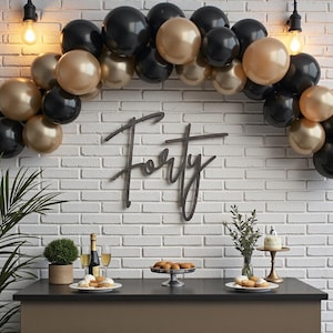 Puede incluir: Una escena de fiesta con una mesa negra, una pared de ladrillos blancos y un arco de globos en negro y dorado. La palabra "Forty" se muestra en la pared. La mesa contiene comida, bebidas y un pastel peque&ntilde;o, lo que sugiere una celebraci&oacute;n de cumplea&ntilde;os.