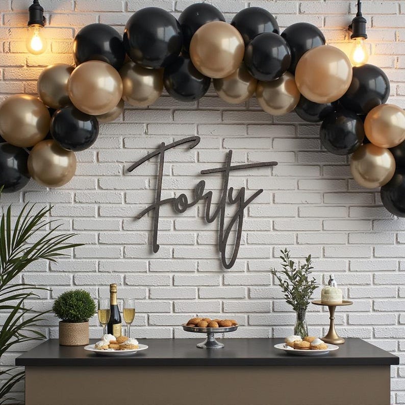 Puede incluir: Una escena de fiesta con una mesa negra, una pared de ladrillos blancos y un arco de globos en negro y dorado. La palabra "Forty" se muestra en la pared. La mesa contiene comida, bebidas y un pastel peque&ntilde;o, lo que sugiere una celebraci&oacute;n de cumplea&ntilde;os.
