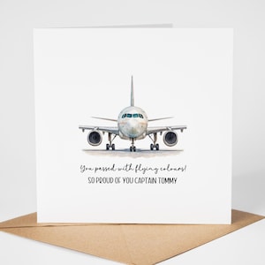 May include: A white greeting card featuring a watercolour illustration of an aeroplane. The text reads, "You passed with flying colours! So proud of you Captain Tommy." The card rests on a brown envelope.