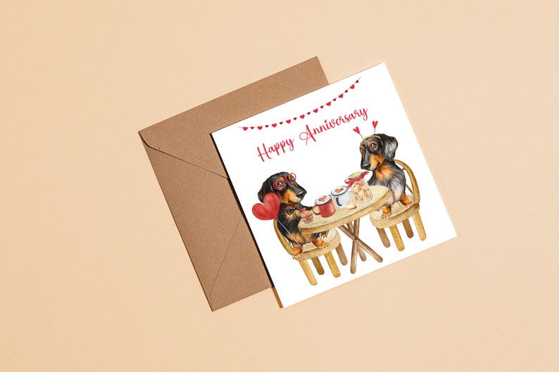 May include: A greeting card with a happy anniversary message. Two dachshund dogs are sitting at a table with a cup of coffee and a heart-shaped balloon. The card has a string of red hearts across the top.