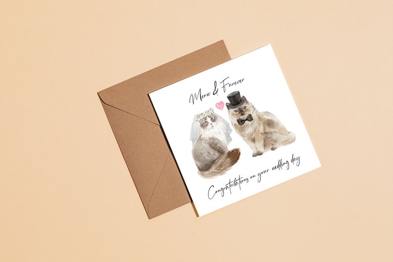 Puede incluir: Una tarjeta blanca con una ilustraci&oacute;n de acuarela de dos gatos vestidos con atuendos de boda. El texto en la tarjeta dice "Meow & Forever. Felicitaciones por su boda."