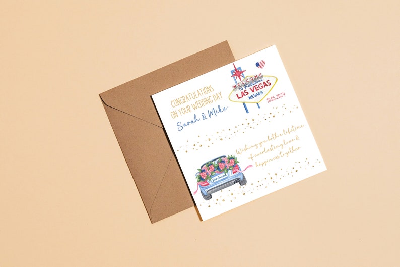 May include: A white wedding card with gold glitter and a watercolor illustration of a car decorated with flowers. The card says "Congratulations on your wedding day Sarah & Mike" and "Wishing you both a lifetime of everlasting love & happiness together". The card also features a sign that says "Welcome to Fabulous Las Vegas Nevada" with a red heart and a small American flag.