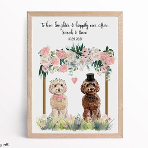 May include: A framed print featuring two illustrated dogs under a floral arch. The dogs are dressed for a wedding, with one wearing a bow tie and the other a top hat. Text at the top reads "To love, laughter & happily ever after..." with names and a date.