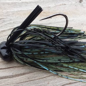 May include: Black and green fishing lure with a black hook and a black and green skirt.
