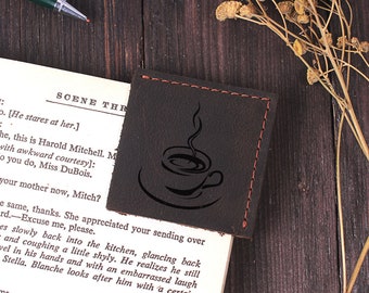May include: A brown leather coaster with a red stitched border. The coaster features a black silhouette of a coffee cup with steam rising from it. The text "YOUR CUSTOM ENGRAVING" is printed in white on a dark brown surface below the coaster.