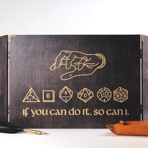 May include: A dark wood folding game board with a hand and dice graphic. The board has the text "If you can do it, so can I."