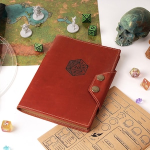 May include: A red leather journal with a D20 symbol, dice, miniature figures, a map, and a quill pen. Two decorative skulls and various polyhedral dice are scattered around the journal, suggesting a tabletop role-playing game theme.