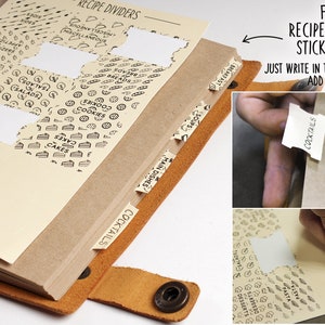 K&ouml;nnte beinhalten: Eine Nahaufnahme eines Rezeptbuchs mit einem Satz Rezept-Trennbl&auml;tter. Die Trennbl&auml;tter sind aus Papier und haben verschiedene Designs, darunter Kuchen, Kekse und Cocktails. Der Text "FREE RECIPE DIVIDERS STICKER PACK" steht auf der Seite. Der Text "JUST WRITE IN THE NOTES TO ORDER ADD DIVIDERS" steht ebenfalls auf der Seite.