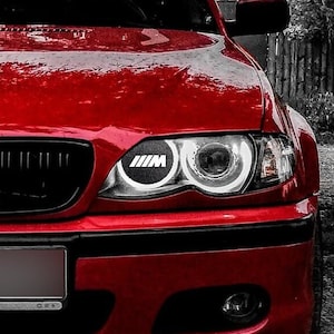 May include: A red BMW car with a black grill and headlights. The car has a license plate that says "BMW".