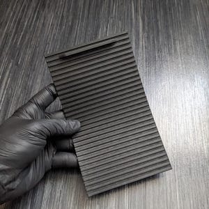 May include: Black plastic car vent cover with a ribbed texture. The cover is designed to fit over a car's air vent to block airflow.
