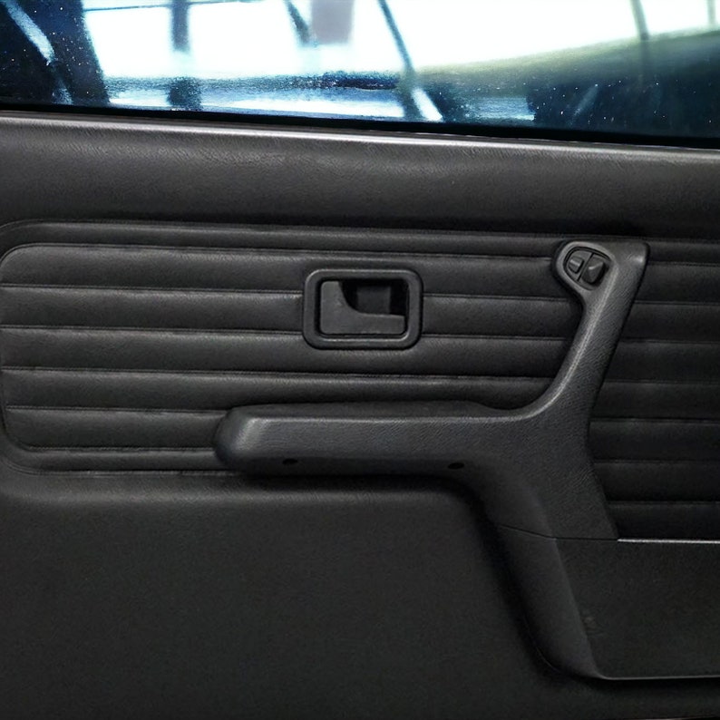 Puede incluir: Panel de puerta de coche de cuero negro con una manija de puerta, un reposabrazos y controles de ventana.