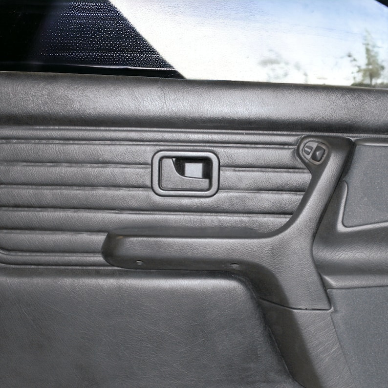 Puede incluir: Panel de puerta de coche de cuero negro con un dise&ntilde;o texturizado, una manija de puerta y una manivela de ventana.