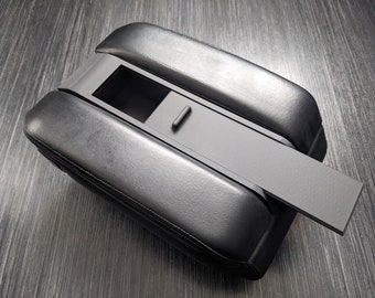 Könnte beinhalten: Schwarze Leder-Mittelkonsolenarmlehne mit einem grauen Staufach und einem Schiebedeckel.