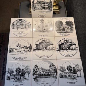 May include: A collection of nine square ceramic tiles, each featuring a black and white illustration of a historical building or landmark. The tiles include text identifying the locations, such as "Longfellow House" and "Irving House."