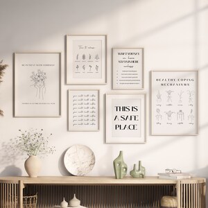 May include: A collection of framed art prints with minimalist line drawings and text, including the phrases "Be Patient With Yourself" and "This Is A Safe Place." The prints are displayed above a wooden console table with decorative items.