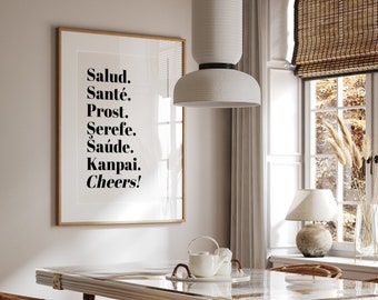 Può includere: Una sala da pranzo con un tavolo e sedie bianche con sedute in vimini intrecciato. Il tavolo ha un piano in marmo bianco e dettagli dorati. Una stampa incorniciata con il testo "Salud. Santé. Prost. Serefe. Saúde. Kanpai. Cheers!" è appesa al muro.