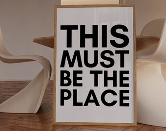 May include: A framed print with the text "THIS MUST BE THE PLACE" in black bold letters on a white background.