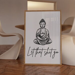 May include: A black and white illustration of Buddha sitting in meditation with the text "Let that shit go" below him. The illustration is on a white background and framed in a light wood frame.