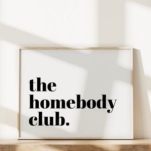 K&ouml;nnte beinhalten: Ein gerahmter Druck mit dem Text "the homebody club." in schwarzen Fettdruck auf wei&szlig;em Hintergrund.