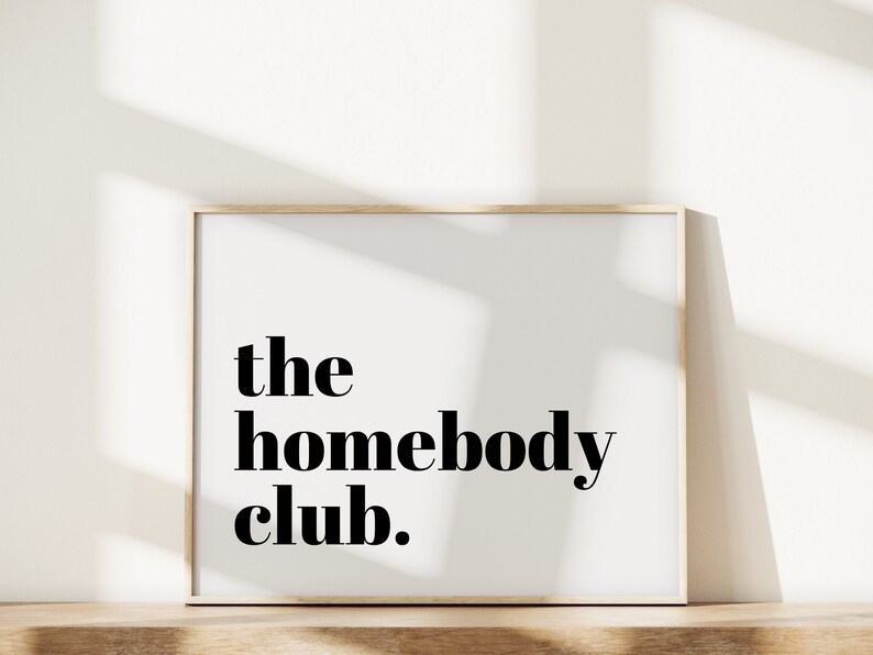 K&ouml;nnte beinhalten: Ein gerahmter Druck mit dem Text "the homebody club." in schwarzen Fettdruck auf wei&szlig;em Hintergrund.
