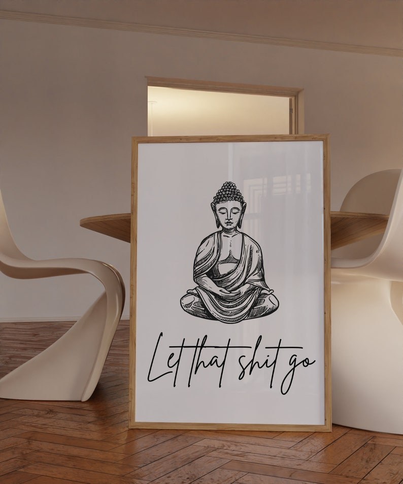May include: A black and white illustration of Buddha sitting in meditation with the text "Let that shit go" below him. The illustration is on a white background and framed in a light wood frame.