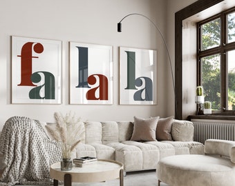 May include: Three framed art prints with the letters "FALA" in a modern font. The letters are in shades of red, green, and blue. The prints are displayed above a beige sofa in a well-lit living room.