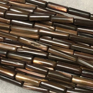 May include: A strand of brown iridescent glass beads, each bead is a long, thin cylinder.