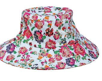 Könnte beinhalten: Ein weißer Bucket-Hut mit einem Blumendruck mit rosa, roten, orangefarbenen und grünen Blumen.