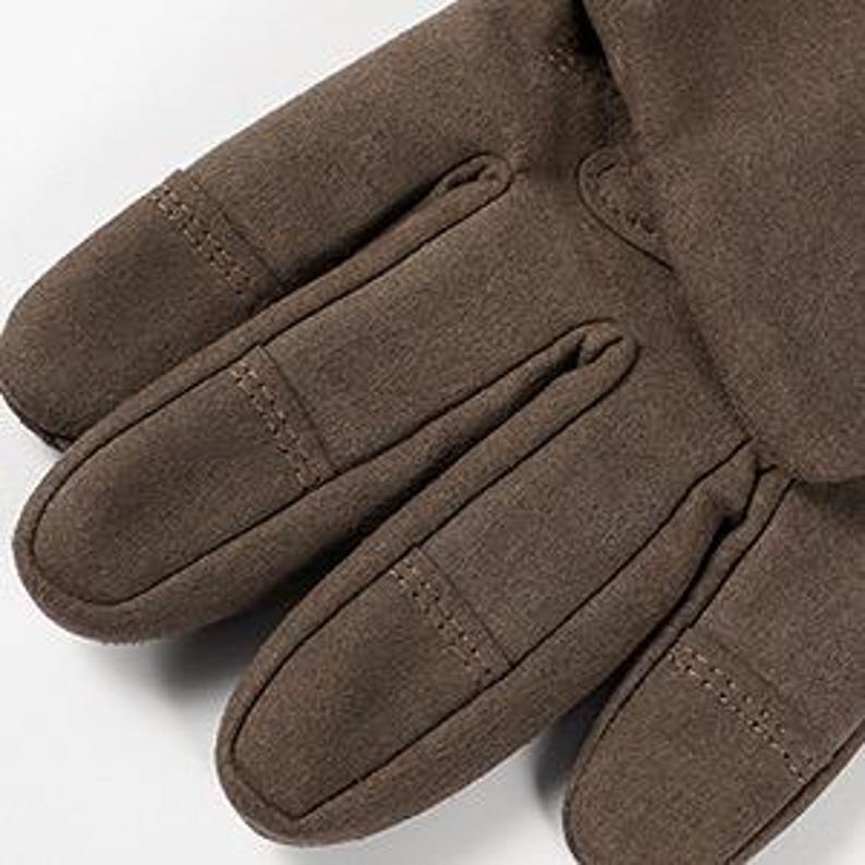 Op de afbeelding: Close-up van bruine leren handschoenen met een textuur. De handschoenen hebben een naaddetail op de vingers en een manchet aan de pols.